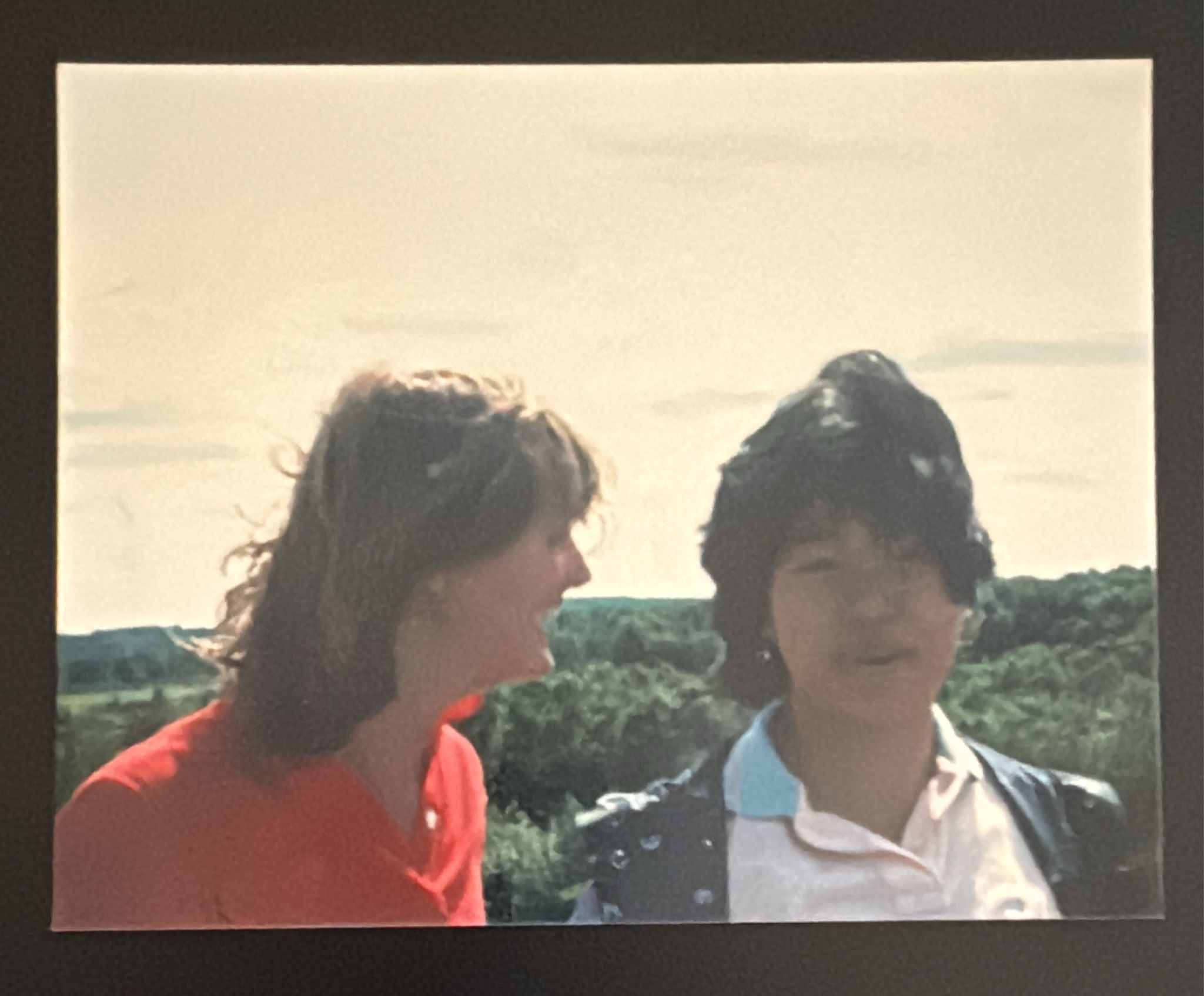 Grainy colour photo of two people in close up, laughing.